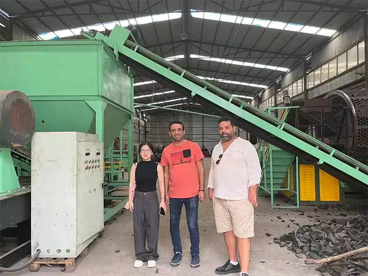 Pengunjung kami berdiri di pabrik daur ulang ban di samping peralatan pengolahan karet