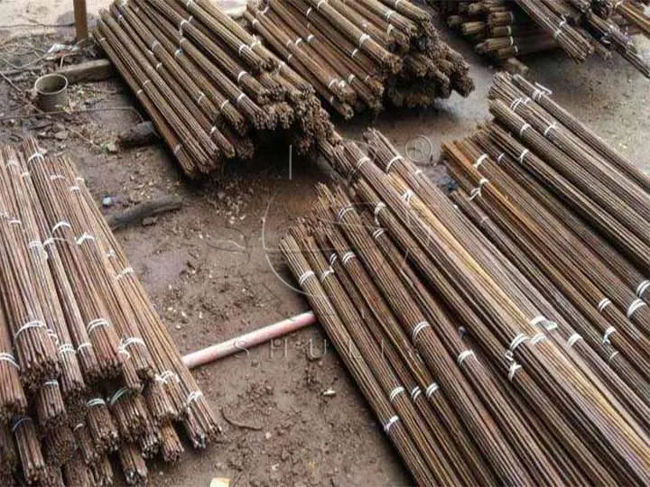 Bundles of bent, rusted rebar stacked on the ground for scrap recycling